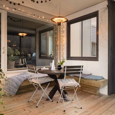 Innglasset veranda med spisebord, benk med puter, lyslenker og grill
