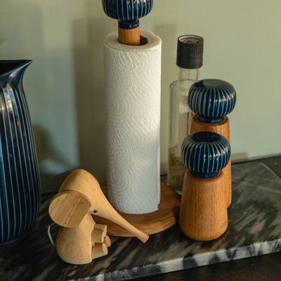 Kjøkkenbenk med papirholder, kvernsett, trefigurer og blå vase