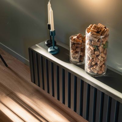 Stearinlys og glasskrukker med kork på oppbevaringsbenk i stue