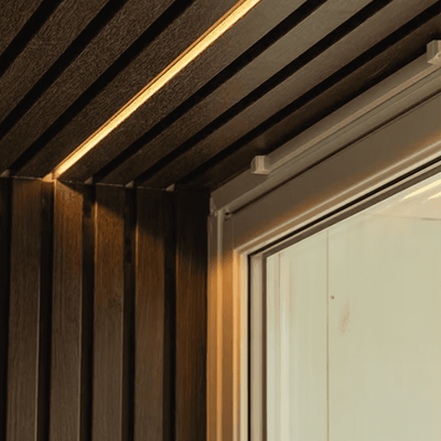 Nærbilde av lamellpanel i tre med innfelt LED-lys ved vindu