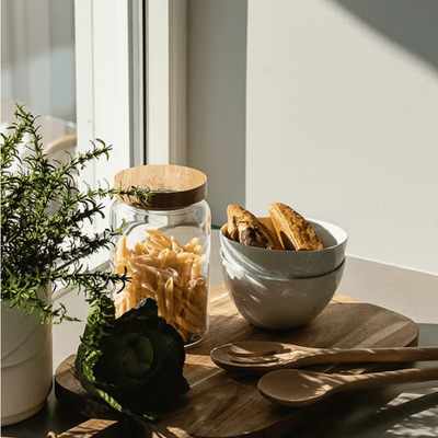 Skjærefjøl med pasta, brød og treskjeer ved vindu