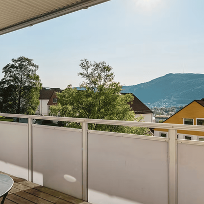Balkong med utsikt over Bergen, fjell og oransje trehus