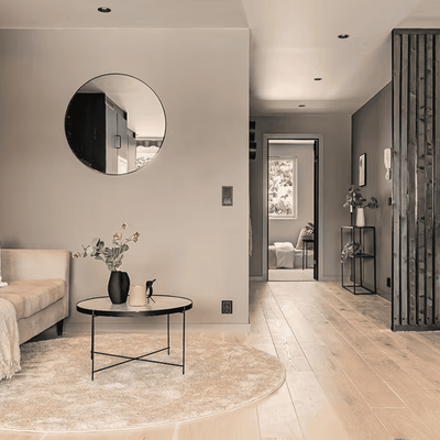 Stue med rundt speil, beige sofa og lyst tregulv