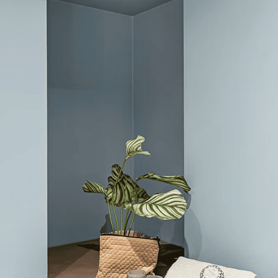 Detalj av badeinnredning med plante, håndklær og lys i blåtonet hjørne