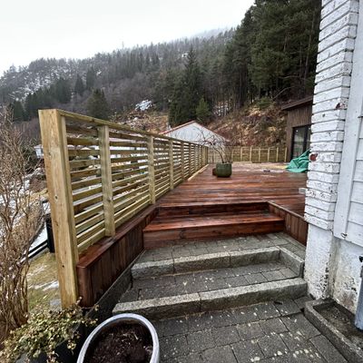 Terrasse i mørkbeiset tre med spilevegg og trapp i granitt en vinterdag